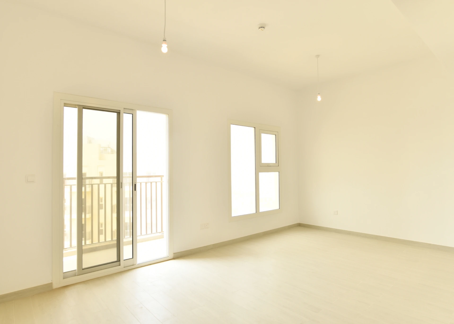 Living room with access to the balcony in a 2-bedroom apartment for sale in Al Rimth 13, Remraam, Dubai.